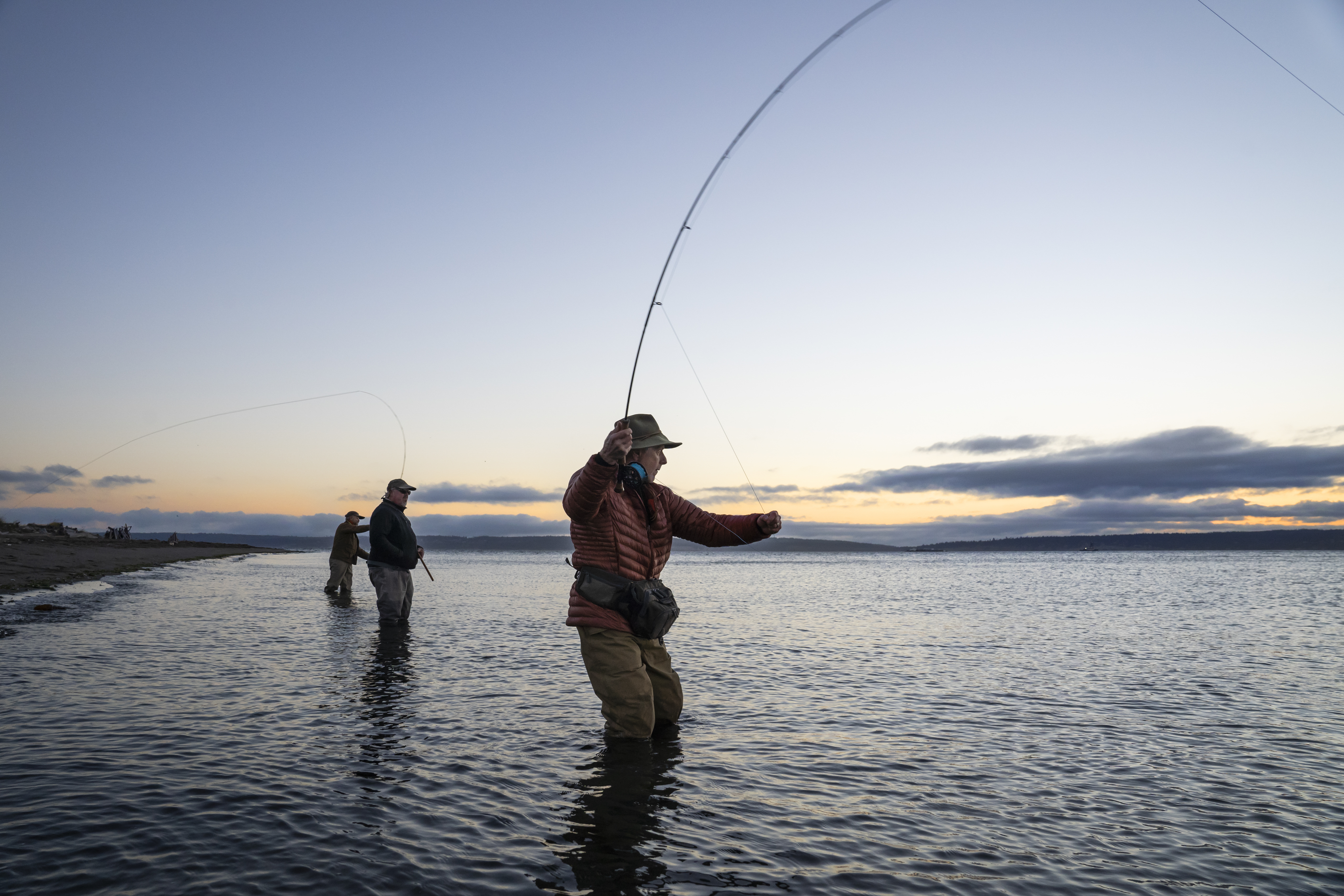 Three fisherman casting their line in the early morning water