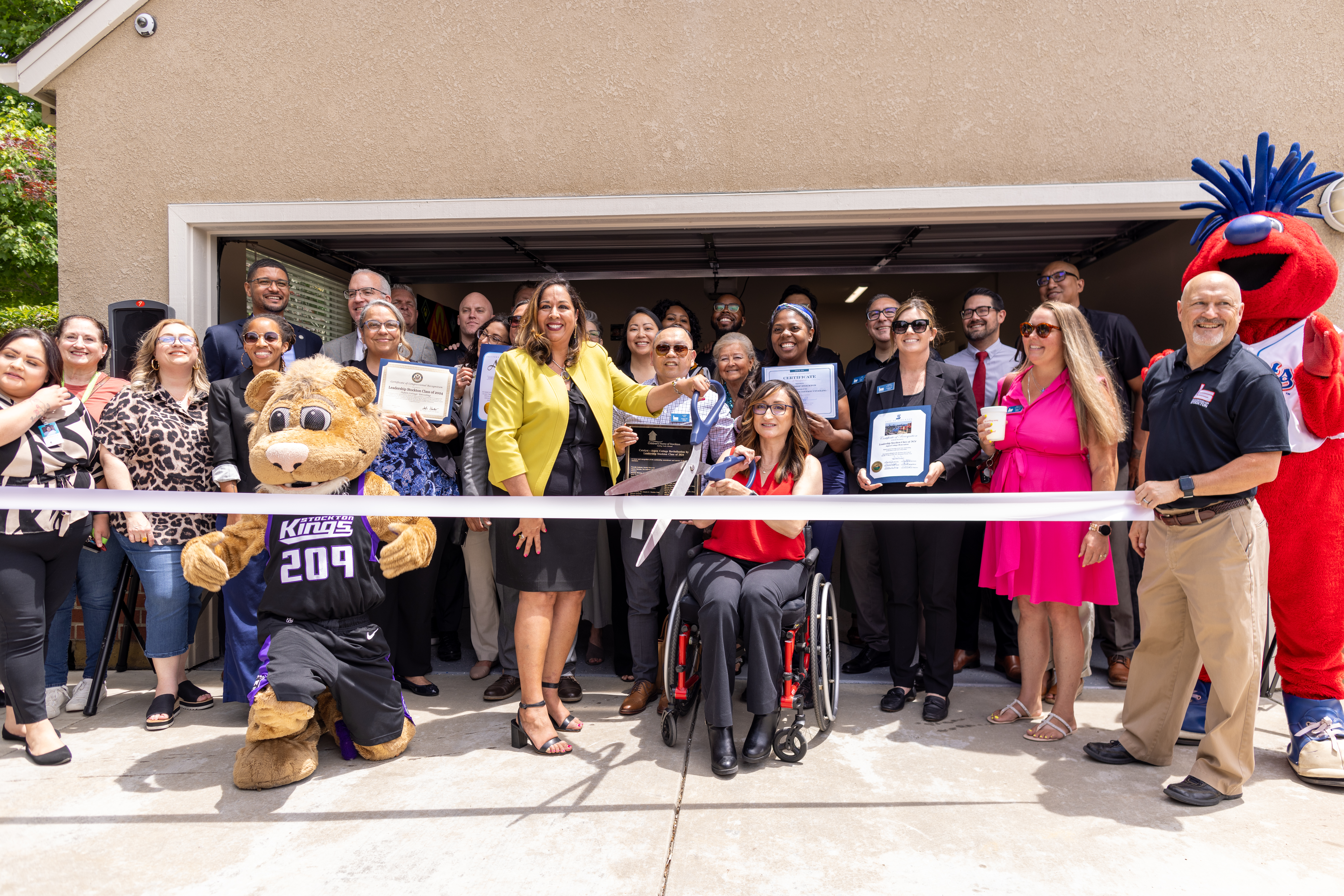 Group of community members and mascots at a ribbon-cutting ceremony for Aspen Cottage at the Children's Home of Stockton.